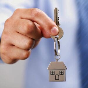 Hand holding house-shaped key on keyring